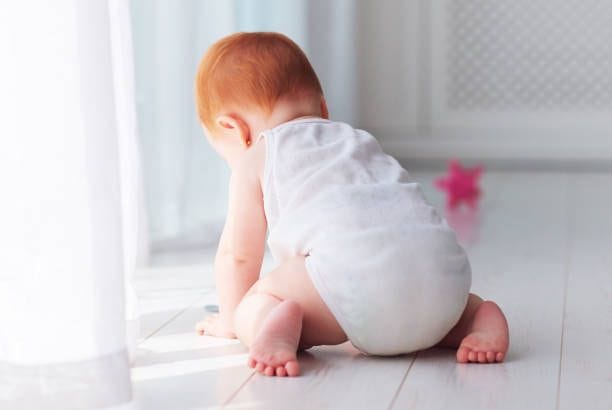 Cute little infant baby girl crawling around the house at sunny day